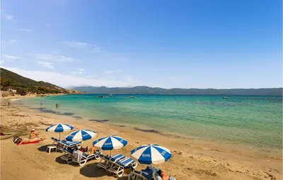 a group of beach chairs with umbrellas on a beach at Cozy Apartment In Ajaccio With Wifi in Ajaccio