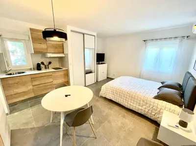 a bedroom with a bed and a table and a kitchen at Appartement Hypercentre Parking Gratuit in Ajaccio