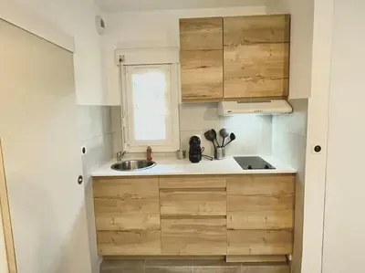 a small kitchen with wooden cabinets and a sink at Appartement Hypercentre Parking Gratuit in Ajaccio