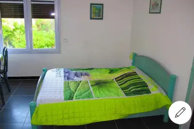 a green bed in a room with a window at F1 calme et proche des plages in Coti-Chiavari