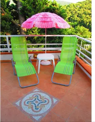 two green chairs and a table with a pink umbrella at F1 calme et proche des plages in Coti-Chiavari