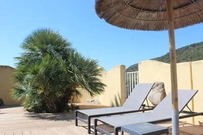 two lounge chairs and an umbrella on a patio at MINI VILLA PALOMBAGGIA - Piscine chauffée in Porto-Vecchio