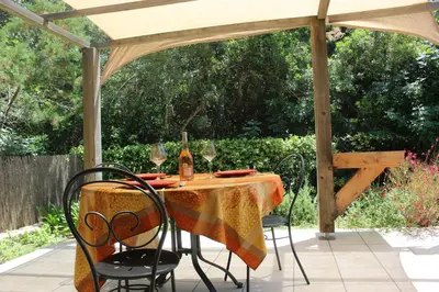 a table with chairs and wine glasses on a patio at MINI VILLA PALOMBAGGIA - Piscine chauffée in Porto-Vecchio
