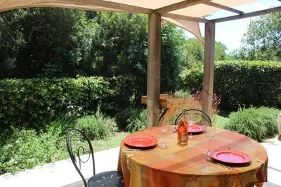 a table with red plates on it under an umbrella at MINI VILLA PALOMBAGGIA - Piscine chauffée in Porto-Vecchio