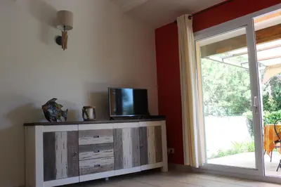 a room with a tv on a dresser with a sliding glass door at MINI VILLA PALOMBAGGIA - Piscine chauffée in Porto-Vecchio