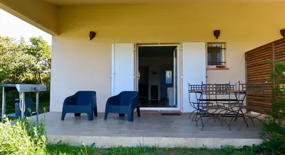 a patio with two blue chairs and a table at Appartements avec jardin entre Porto-Vecchio et Figari - Casa Mattiste in Sotta