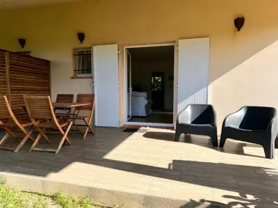 a patio with chairs and a table and a bed at Appartements avec jardin entre Porto-Vecchio et Figari - Casa Mattiste in Sotta
