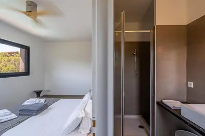 a small bathroom with a bed and a shower at Les Villas de Lorello in Porticcio