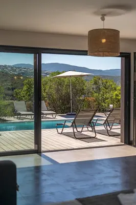 a patio with chairs and an umbrella and a pool at Les Villas de Lorello in Porticcio