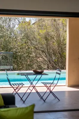 two chairs and a table in front of a pool at Les Villas de Lorello in Porticcio
