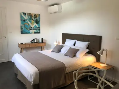 a bedroom with a large bed and a table at Villa Limone, maison d'hôtes in Calenzana