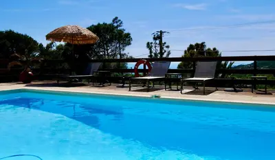 a swimming pool with two chairs and an umbrella at Bas de villa vue mer & piscine in Coti-Chiavari