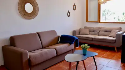 a living room with a couch and a table at Bas de villa vue mer & piscine in Coti-Chiavari