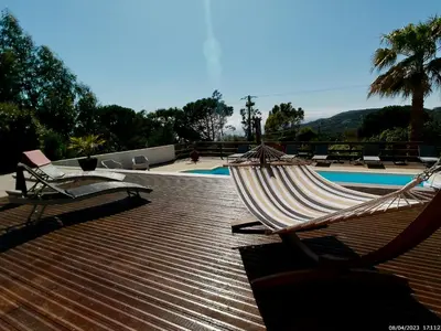 a hammock sitting on a deck next to a pool at Bas de villa vue mer & piscine in Coti-Chiavari
