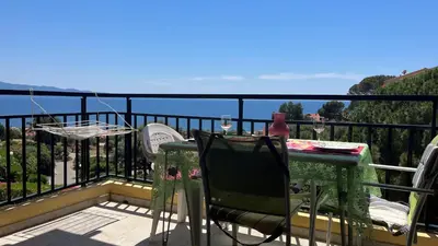 a table and chairs on a balcony with a view of the ocean at Un Havre de Paix aux Sanguinaires in Ajaccio