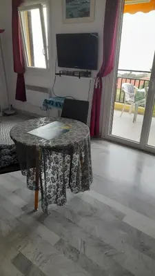 a room with a table and a television and a balcony at Un Havre de Paix aux Sanguinaires in Ajaccio
