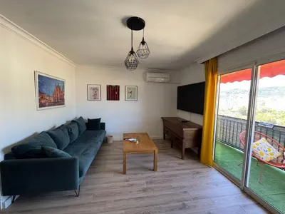 a living room with a blue couch and a tv at T3 Cosy in Ajaccio