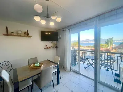 a dining room with a table and chairs and a balcony at Appartement cosy, vue mer à 5 min à pied de la mer in Grosseto-Prugna