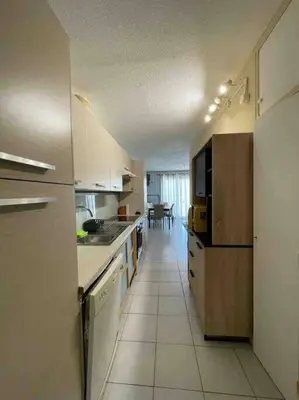 a kitchen with white cabinets and a white tile floor at Appartement cosy, vue mer à 5 min à pied de la mer in Grosseto-Prugna
