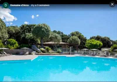 a large blue swimming pool with chairs and umbrellas at Appart Stella résidence standing, vue panoramique in Porto-Vecchio