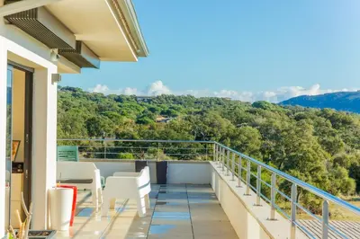 a balcony with white chairs and a view of the mountains at Appart Stella résidence standing, vue panoramique in Porto-Vecchio