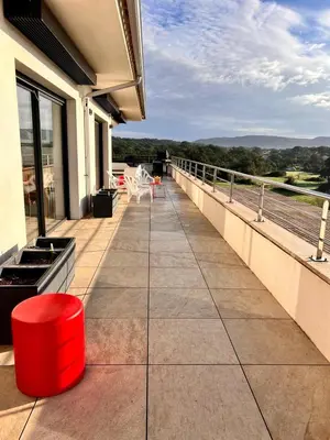 a balcony with a red stool and chairs on a building at Appart Stella résidence standing, vue panoramique in Porto-Vecchio