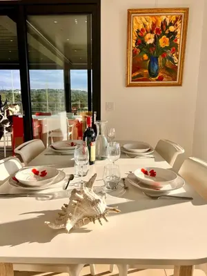 a table with white plates and a painting on the wall at Appart Stella résidence standing, vue panoramique in Porto-Vecchio