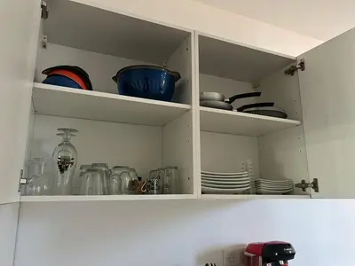 a white cabinet filled with dishes and plates at T2 vue mer - entre aéroport et centre-ville in Ajaccio