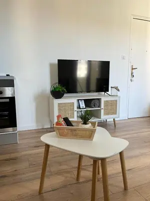a living room with a table and a tv at T2 vue mer - entre aéroport et centre-ville in Ajaccio