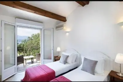 a bedroom with a bed and a large window at Villa Casetta Bianca 2 chambres, Piscine et accès mer in Porto-Vecchio