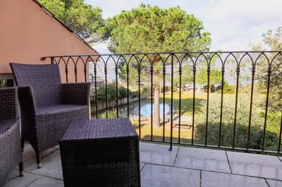 a balcony with two chairs and a fence with a pool at Villa Casetta Bianca 2 chambres, Piscine et accès mer in Porto-Vecchio