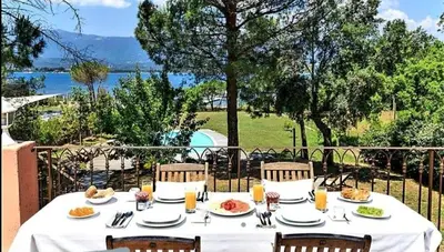 a table with plates of food on top of a balcony at Villa Casetta Bianca 2 chambres, Piscine et accès mer in Porto-Vecchio
