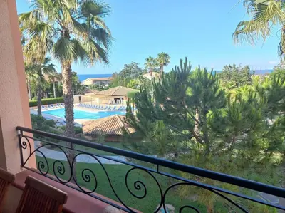 a balcony with a view of a pool and palm trees at Appartement de vacances Marine de Bravone - Corse in Linguizzetta