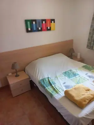 a bedroom with a bed and two tables with lamps at Appartement de vacances Marine de Bravone - Corse in Linguizzetta