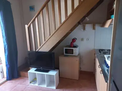 a kitchen with a staircase with a microwave and a television at Appartement de vacances Marine de Bravone - Corse in Linguizzetta