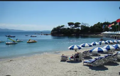 a beach with chairs and umbrellas and boats in the water at Superbe Pieds dans l eau ajaccio face à la mer plage de sable fin route des îles des sanguinaires in Ajaccio