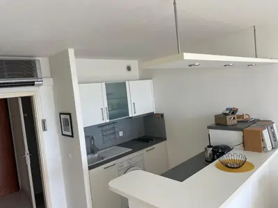 a kitchen with white cabinets and a white counter top at Superbe Pieds dans l eau ajaccio face à la mer plage de sable fin route des îles des sanguinaires in Ajaccio