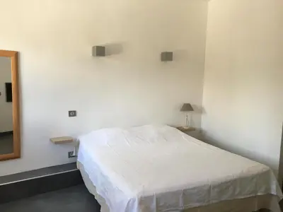 a bedroom with a white bed and a mirror at Residence Les Jardins de Sainte-Lucie 