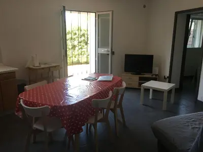 a room with a table and chairs and a television at Residence Les Jardins de Sainte-Lucie 