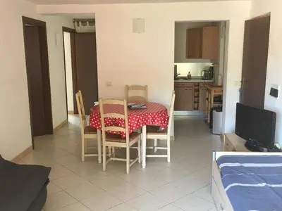 a room with a table and chairs and a kitchen at Residence Les Jardins de Sainte-Lucie 