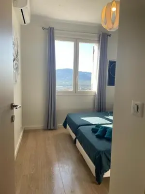 a bedroom with a bed and a large window at Superbe appartement en centre ville in Porto-Vecchio