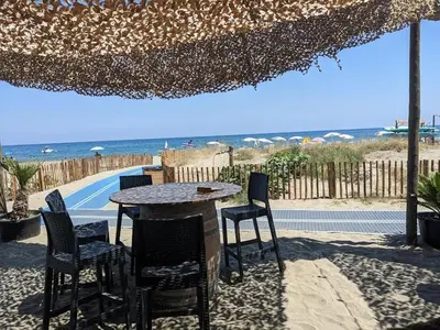 a table and chairs under an umbrella on the beach at Entre Mer et Montagne in Venzolasca