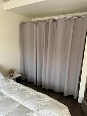 a bedroom with white curtains next to a bed at Entre Mer et Montagne in Venzolasca