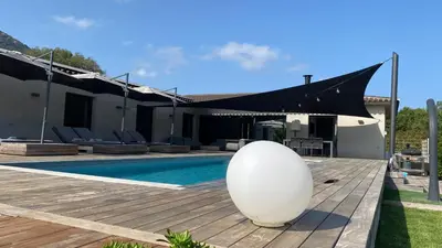 a villa with a swimming pool and a black awning at Villa A Licciola in Porto-Vecchio