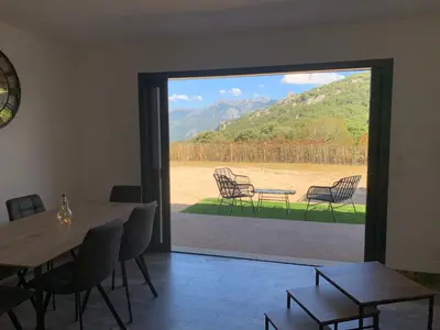 a dining room with a table and chairs and a sliding glass door at A casetta maison de plain pied in Sartène