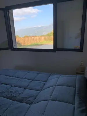 a bedroom with a window looking out at a field at A casetta maison de plain pied in Sartène
