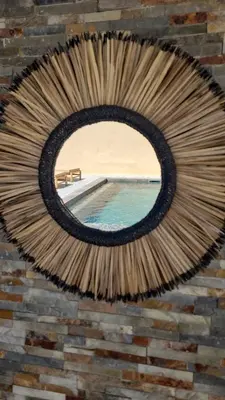 a round mirror on a brick wall with a swimming pool at Villa individuelle 3 chambres - 6 pers in Calvi