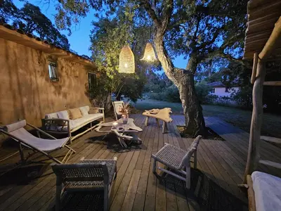 a wooden deck with a table and chairs and a tree at Maison Pinarellu plage à pieds in Zonza