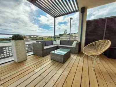 a deck with a couch and a chair on a balcony at Charmant T3 à Porticcio in Porticcio