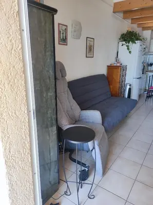 a living room with a blue couch and a table at A 5 mn à pied de la mer, piscine ,tennis, paillote in Cervione